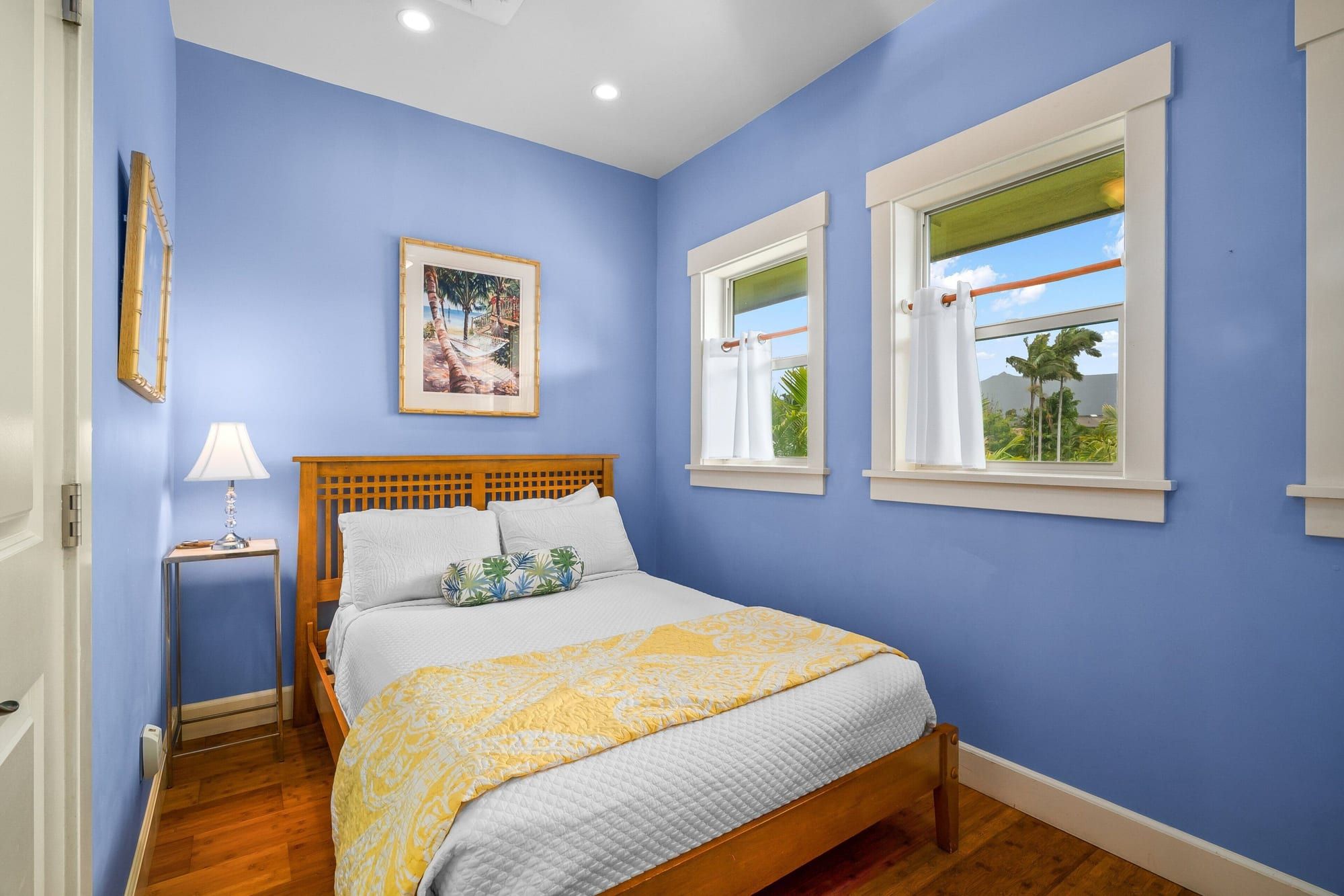 A blue bedroom with a full bed and garden views