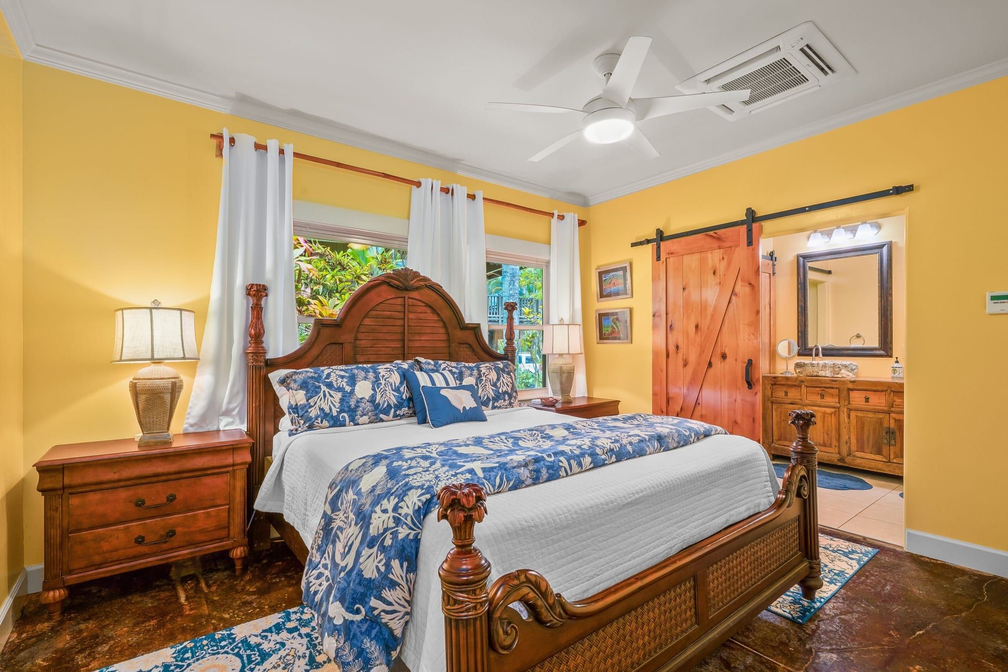 A king bed with blue floral bedding and a barn door to the bath