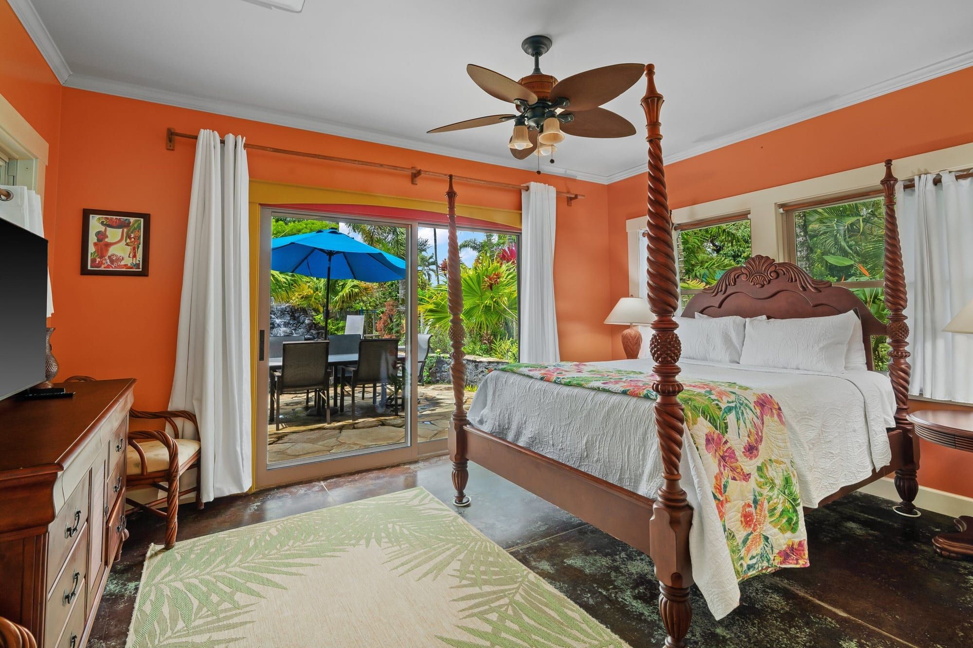 A bedroom with a carved four-poster bed and sliding doors to the lanai