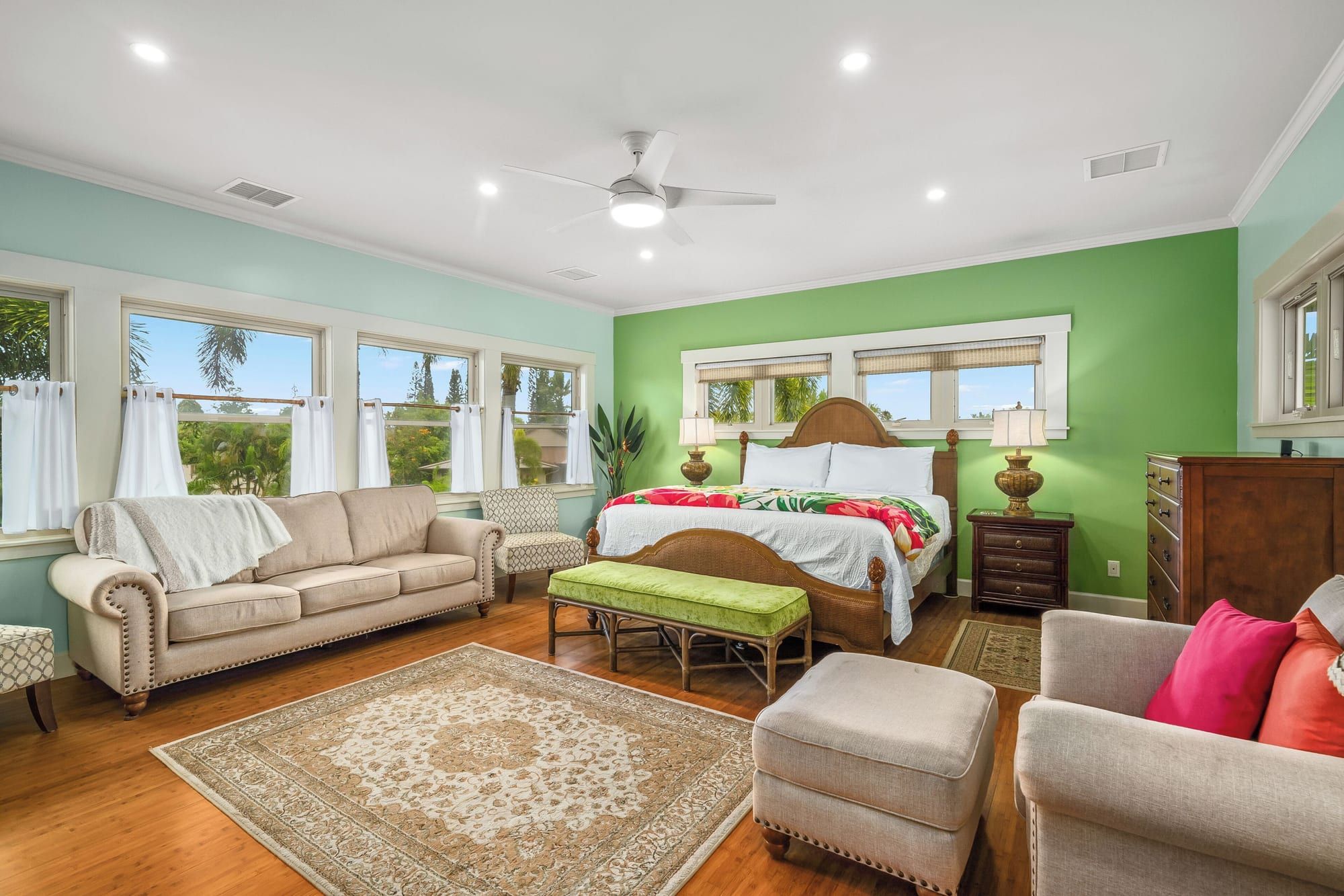 The primary suite with a king bed, sofa and a wall of windows