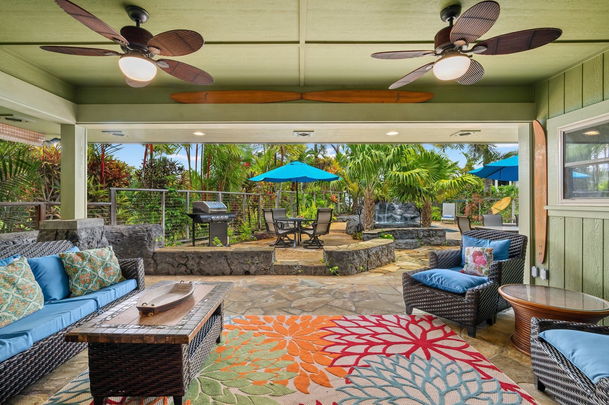 The covered lanai with wicker sofas and ceiling fans, looking out to the pool