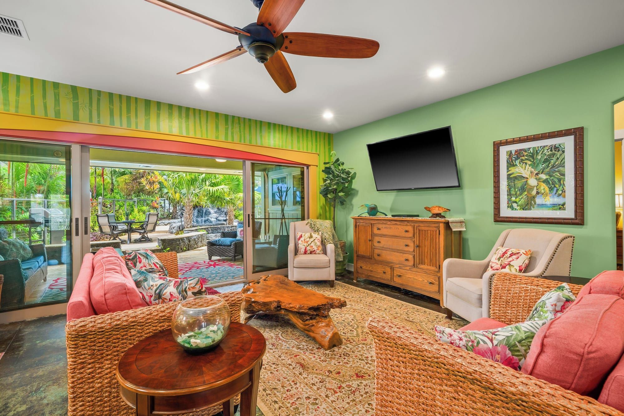 The living room with coral sofas, a live-edge coffee table and doors open to the lanai