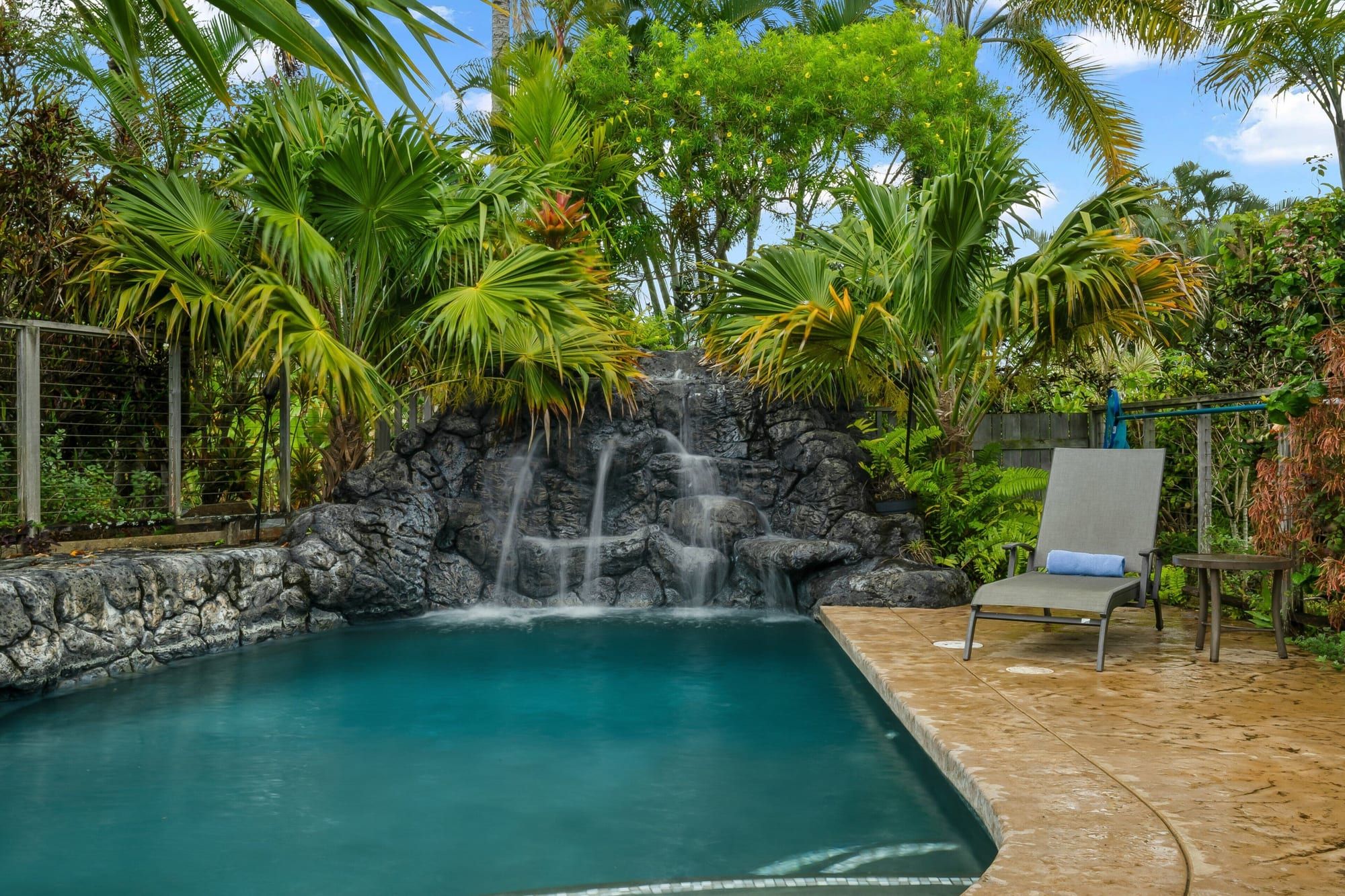 The lava-rock waterfall spilling into the pool under tall palms