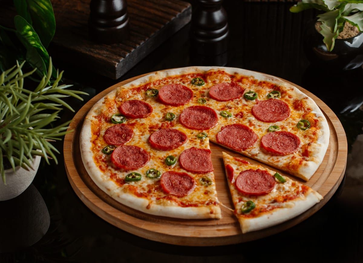 A pepperoni pizza with one slice cut on a wooden board